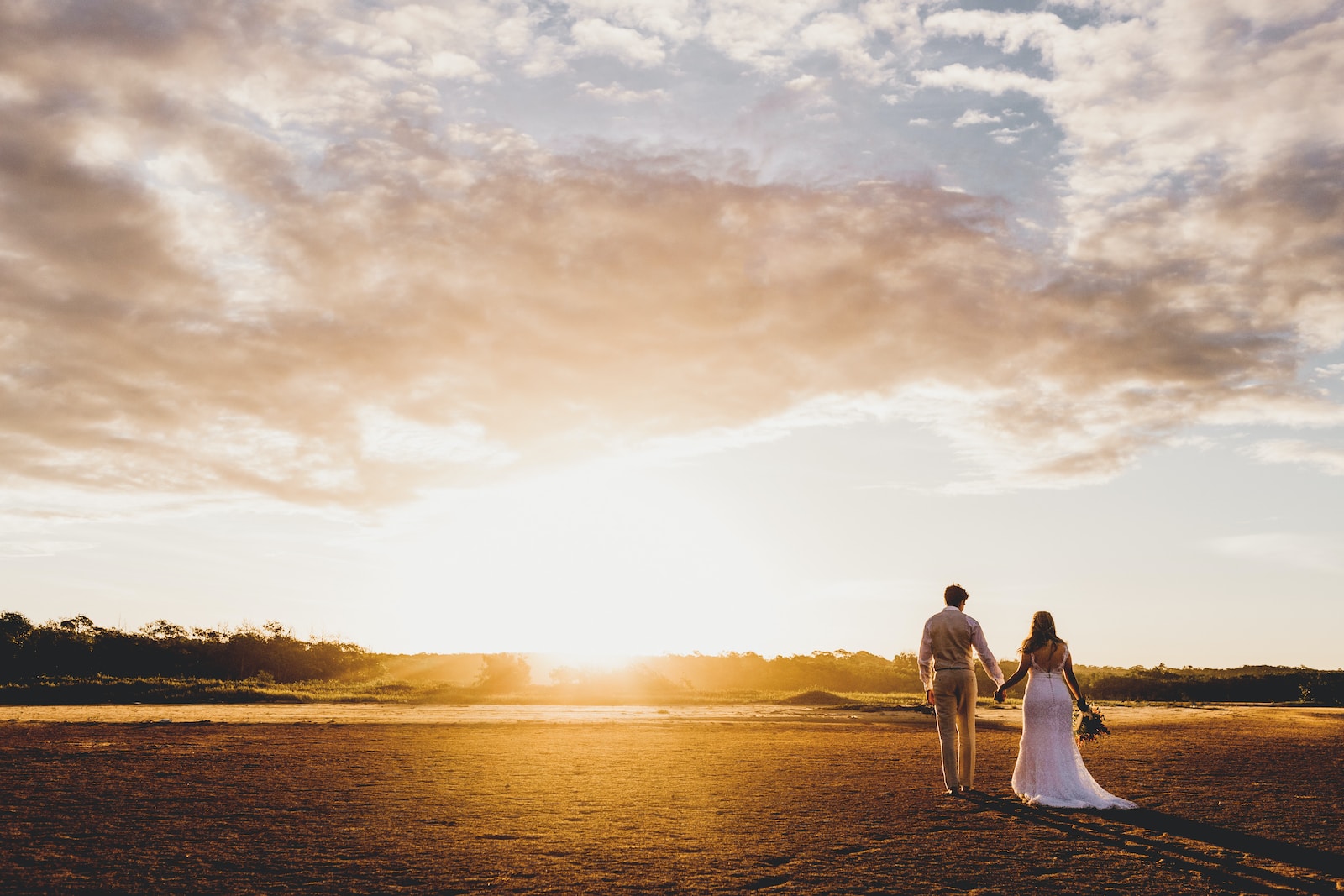 couple standing on road under sunset